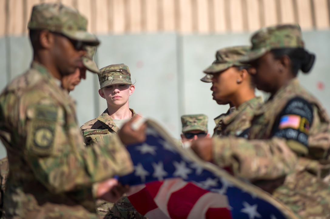 U.S. Air Force Senior Airman Chelsea Shields, center, and members of the Bagram air honor guard fold the American flag during a Memorial Day retreat ceremony at Bagram Airfield, Afghanistan, May 25, 2015.