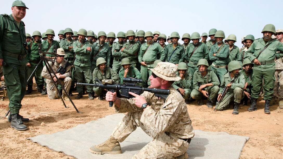 Sgt. Brian Souza, a squad leader with Bravo Company, 1st Battalion, 25th Marine Regiment, demonstrates different firing positions with the M4 rifle to Moroccan soldiers during the first day of African Lion 15, May 15, 2015. Souza, a Cambridge, Mass., native, also taught the assembly and disassembly of the M4 rifle during the training. 