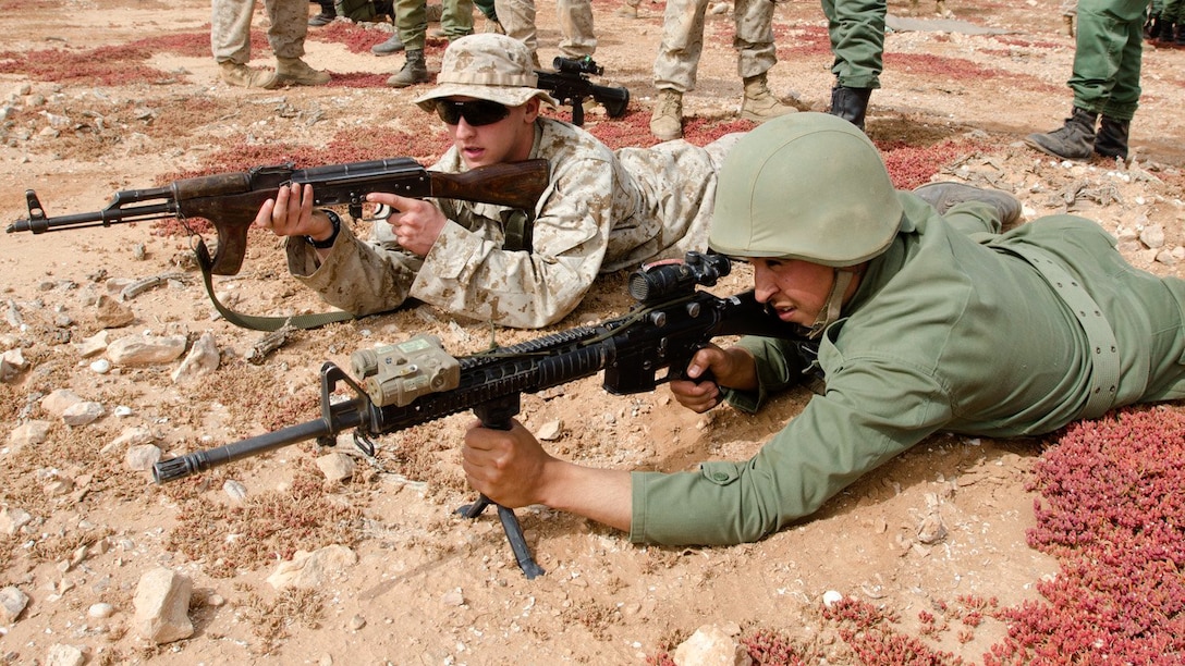 Pfc. Adam Kennedy, an infantryman with Alpha Company, 1st Battalion, 25th Marine Regiment, practices a prone firing stance with an AK-47 assault rifle while his Moroccan shooting partner practices with the M16 A2 rifle during the first day of African Lion 15, May 15, 2015. Kennedy is from Presque Isle, Maine. 