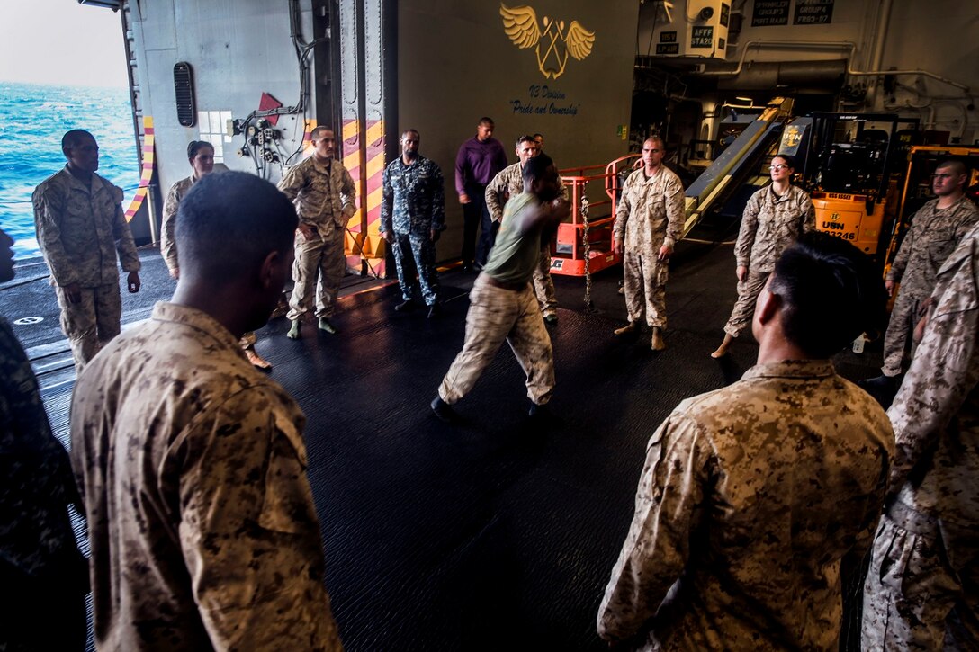 U.S. Marines and Sailors with the 15th Marine Expeditionary Unit and Essex Amphibious Ready Group practice Marine Corps Martial Arts Program drills in the hangar bay of the USS Essex (LHD 2) at sea in the Pacific Ocean, May 23, 2015. The Marines and Sailors are working toward their next MCMAP level belt during their seven-month deployment through the Pacific and Central command areas. (U.S. Marine Corps photo by Cpl. Elize McKelvey/Released)