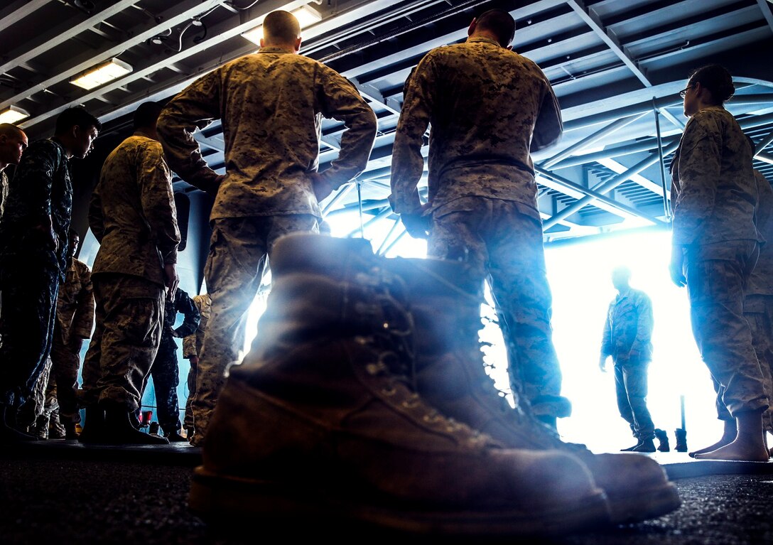 U.S. Marines and Sailors with the 15th Marine Expeditionary Unit and Essex Amphibious Ready Group await instructions during Marine Corps Martial Arts Program training in the hangar bay of the USS Essex (LHD 2) at sea in the Pacific Ocean, May 23, 2015. The Marines and Sailors are working toward their next MCMAP level belt during their seven-month deployment through the Pacific and Central command areas. (U.S. Marine Corps photo by Cpl. Elize McKelvey/Released)