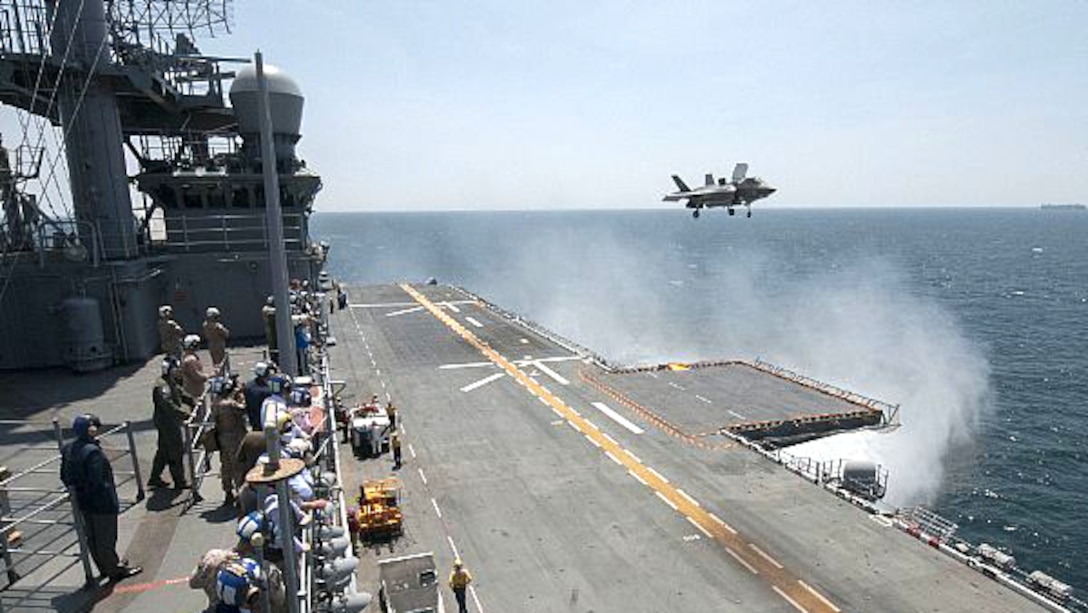 Sailors and distinguished visitors watch an F-35B Lightning II aircraft conduct vertical takeoff and landing flight operations aboard the amphibious assault ship USS Wasp. Wasp is conducting the F-35B first phase operational testing to include flight deck operations, maintenance operations and logistical supply chain operations at sea. 