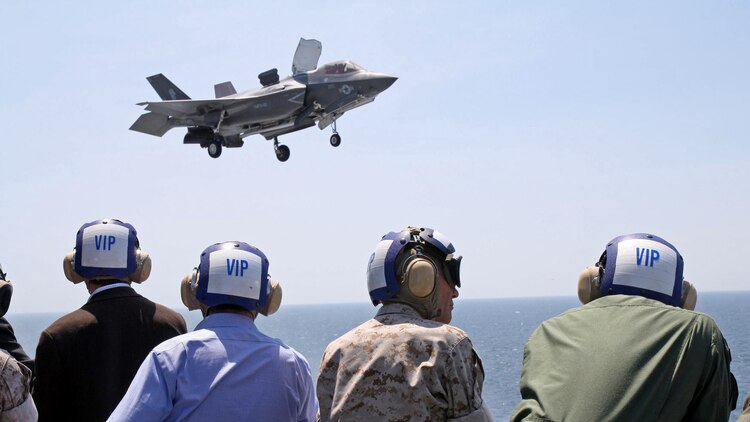 U.S. Air Force Lt. Gen. Christopher C. Bogdan (right), the Program Executive Officer for the F-35 Lightning II Joint Program Office, and U.S. Marine Corps Lt. Gen. Jon Davis, Deputy Commandant Aviation, along with distinguished visitors from the U.S. Department of Defense and the United Kingdom Ministry of Defence, watch as an F-35B lands on the flight deck of USS Wasp off the coast of Virginia, May 20, 2015.  Bogdan and Davis brought a delegation of UK and other distinguished visitors out to USS Wasp for the day to observe F-35B operational testing, and to speak with the U.S. and UK service members participating in the test. Sixteen UK service personnel are embarked aboard USS Wasp, gaining valuable hands-on experience as the UK re-generates its Carrier Strike capability.