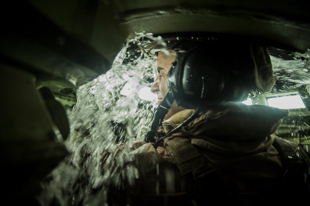 U.S. Marine Cpl. Christopher Jimerson is splashed with water through the turret of an AAV-7 Amphibious Assault Vehicle during an amphibious movement to the USS Rushmore (LSD 47) aboard Marine Corps Base Hawaii, May 19, 2015. Jimerson is a crew chief with Kilo Company, Battalion Landing Team 3rd Battalion, 1st Marine Regiment, 15th Marine Expeditionary Unit. The training focused on amphibious and tactical troop transport using AAVs. (U.S. Marine Corps photo by Sgt. Emmanuel Ramos/Released)