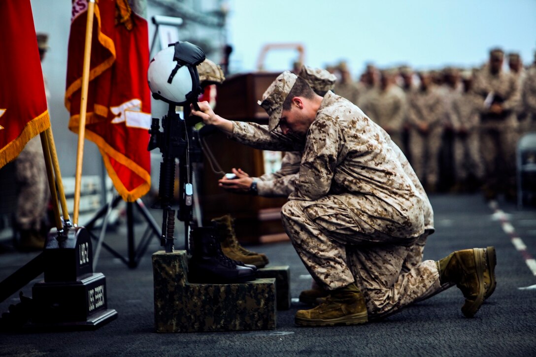 U.S. Marines with the 15th Marine Expeditionary Unit take a moment of silence in front of the memorial of Cpl. Joshua Barron and Lance Cpl. Matthew Determan aboard the flight deck of the USS Essex (LHD 2) at sea in the Pacific Ocean, May 23, 2015. Marines and Sailors with the 15th MEU and the Essex Amphibious Ready Group paused during deployment to pay their respects and honor the two Marines. (U.S. Marine Corps photo by Cpl. Elize McKelvey/Released)