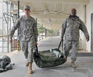 Army Spcs. Adam Schroeder (left) and Bernard Satchell, both with the Georgia National Guard’s 124th Mobile Public Affairs Detachment, preposition the unit’s tents to house unit members should they be called out to assist during the storm expected to hit Georgia today.