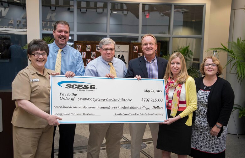 Navy Capt. Amy Burin, commanding officer of Space and Naval Warfare (SPAWAR) Systems Center (SSC) Atlantic, along with Executive Director Steve Dunn, Facilities Manager Darrell Denaux and Energy Program Manager Tom Egbert accept a rebate check from South Carolina Electric and Gas (SCE&G) in the amount of $797,215 May 26 at the Naval Weapons Station - Joint Base Charleston. The check is a result of successful energy savings rebate initiatives under SSC Atlantic’s Energy Savings Performance Contract (ESPC)through Huntsville Center and SCE&G’s EnergyWise for your Business program. 