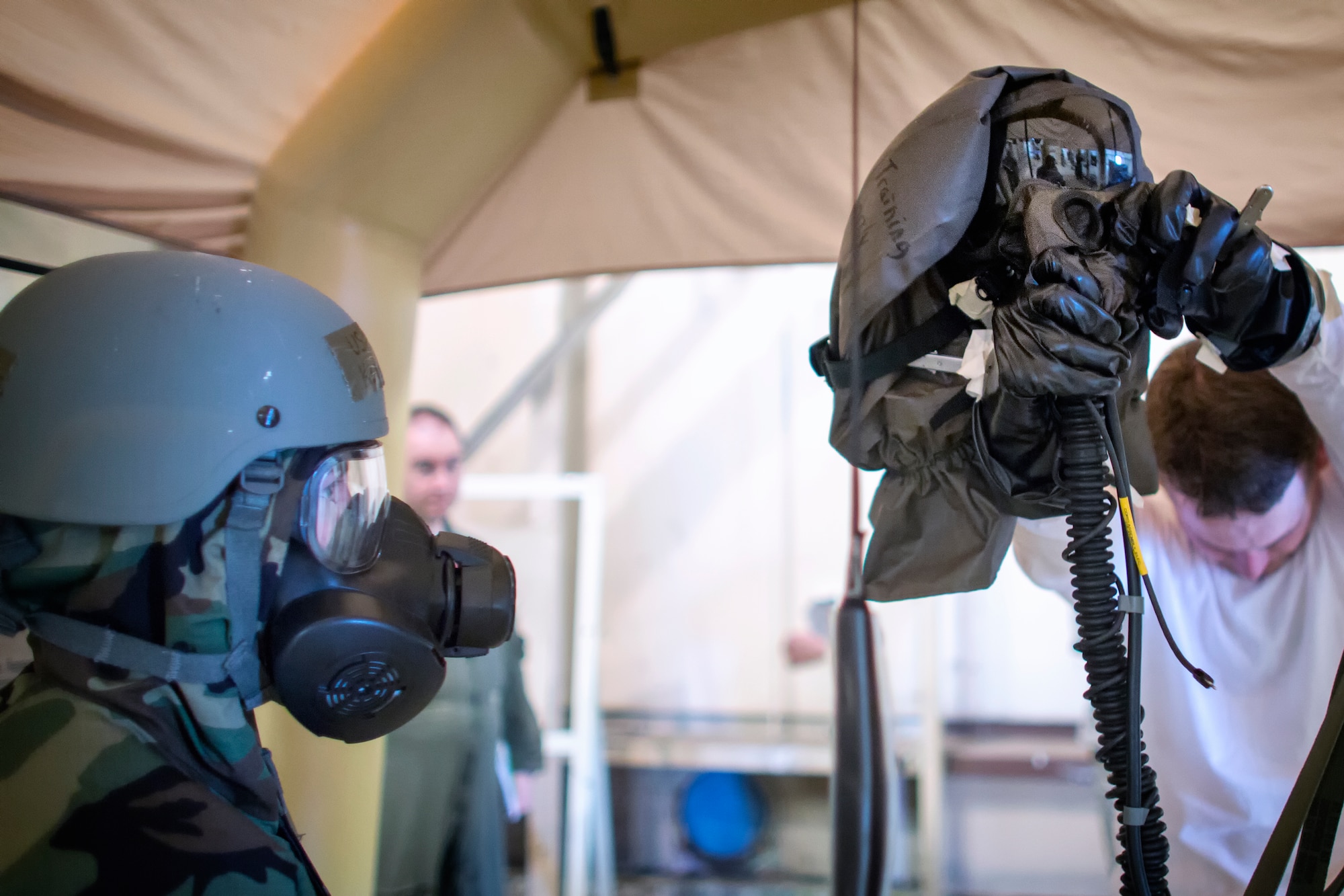 Staff Sgt. Katie Powell, 374th Operations Support Squadron aircrew flight equipment, monitors mask removal during a Samurai Readiness Inspection at Yokota Air Base, Japan, May 20, 2015. Airmen from the 36th Airlift Squadron and 374th OSS performed aircrew decontamination procedures with the Lightweight Inflatable Decontamination System (LIDS). The LIDS takes about 20 minutes to set up and consists of four stations for rinsing off excess chemicals and a process to dispose of contaminated clothing and aircrew equipment. (U.S. Air Force photo by Osakabe Yasuo/Released)