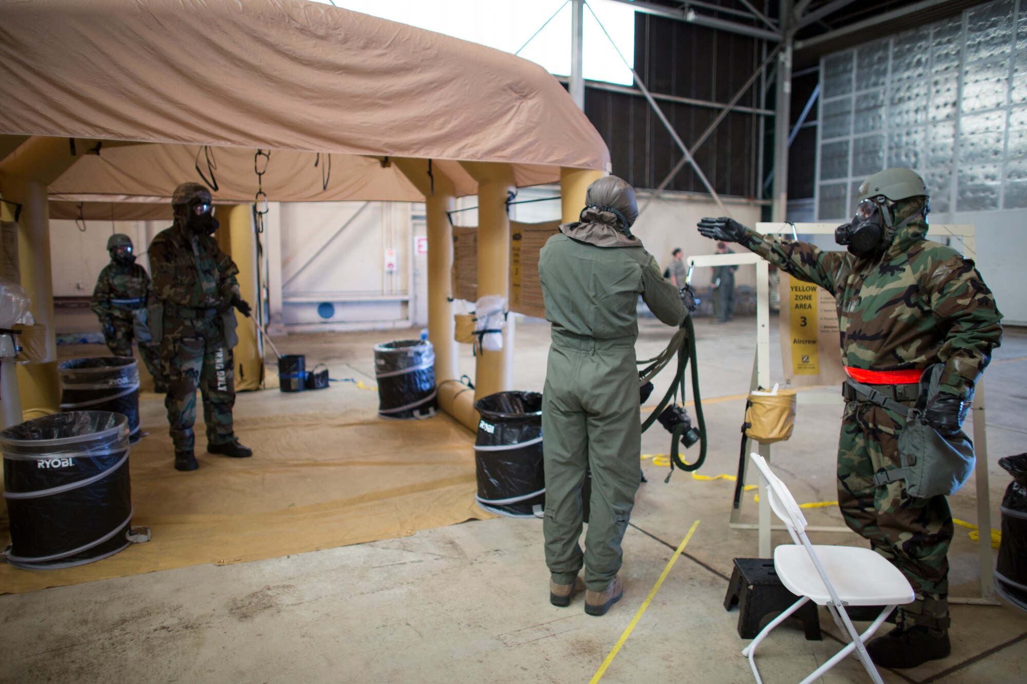 An aircrew member from the 36th Airlift Squadron, center, passes through the third stage of decontamination during a Samurai Readiness Inspection at Yokota Air Base, Japan, May 20, 2015. Airmen from the 36th AS and 374th Operations Support Squadron performed aircrew decontamination procedures with the Lightweight Inflatable Decontamination System (LIDS). The LIDS takes about 20 minutes to set up and consists of four stations for rinsing off excess chemicals and a process to dispose of contaminated clothing and aircrew equipment. (U.S. Air Force photo by Osakabe Yasuo/Released)