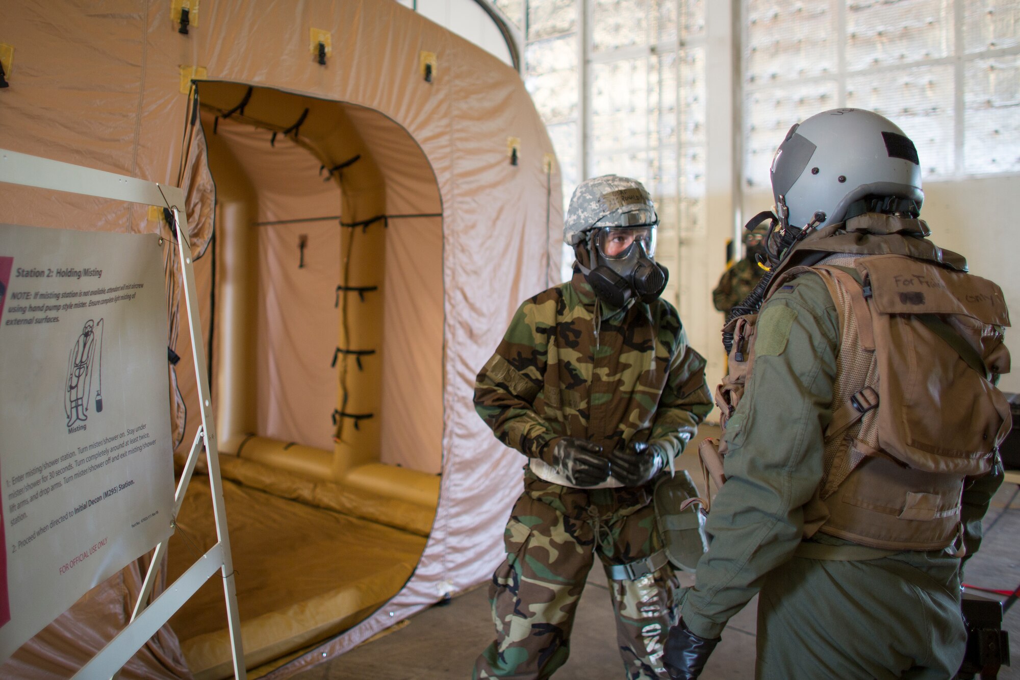 Airman 1st Class Ronald Flanagan, 374th Operations Support Squadron aircrew flight equipment, explains the full body rinse cycle procedure to an aircrew member from the 36th Airlift Squadron at Yokota Air Base, Japan, May 20, 2015, during a Samurai Readiness Inspection. Airmen from the 36th Airlift Squadron and 374th OSS performed aircrew decontamination procedures with the Lightweight Inflatable Decontamination System (LIDS). The LIDS takes about 20 minutes to set up and consists of four stations for rinsing off excess chemicals and a process to dispose of contaminated clothing and aircrew equipment. (U.S. Air Force photo by Osakabe Yasuo/Released)