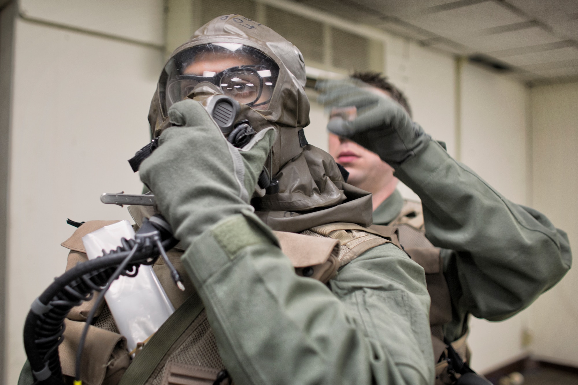 Aircrew from the 36th Airlift Squadron secures the straps on an Aircrew Eye and Respiratory Protection System during a Samurai Readiness Inspection at Yokota Air Base, Japan, May 20, 2015. Airmen from the 36th AS and 374th Operations Support Squadron performed aircrew decontamination procedures with the Lightweight Inflatable Decontamination System (LIDS). The LIDS takes about 20 minutes to set up and consists of four stations for rinsing off excess chemicals and a process to dispose of contaminated clothing and aircrew equipment. (U.S. Air Force photo by Osakabe Yasuo/Released)