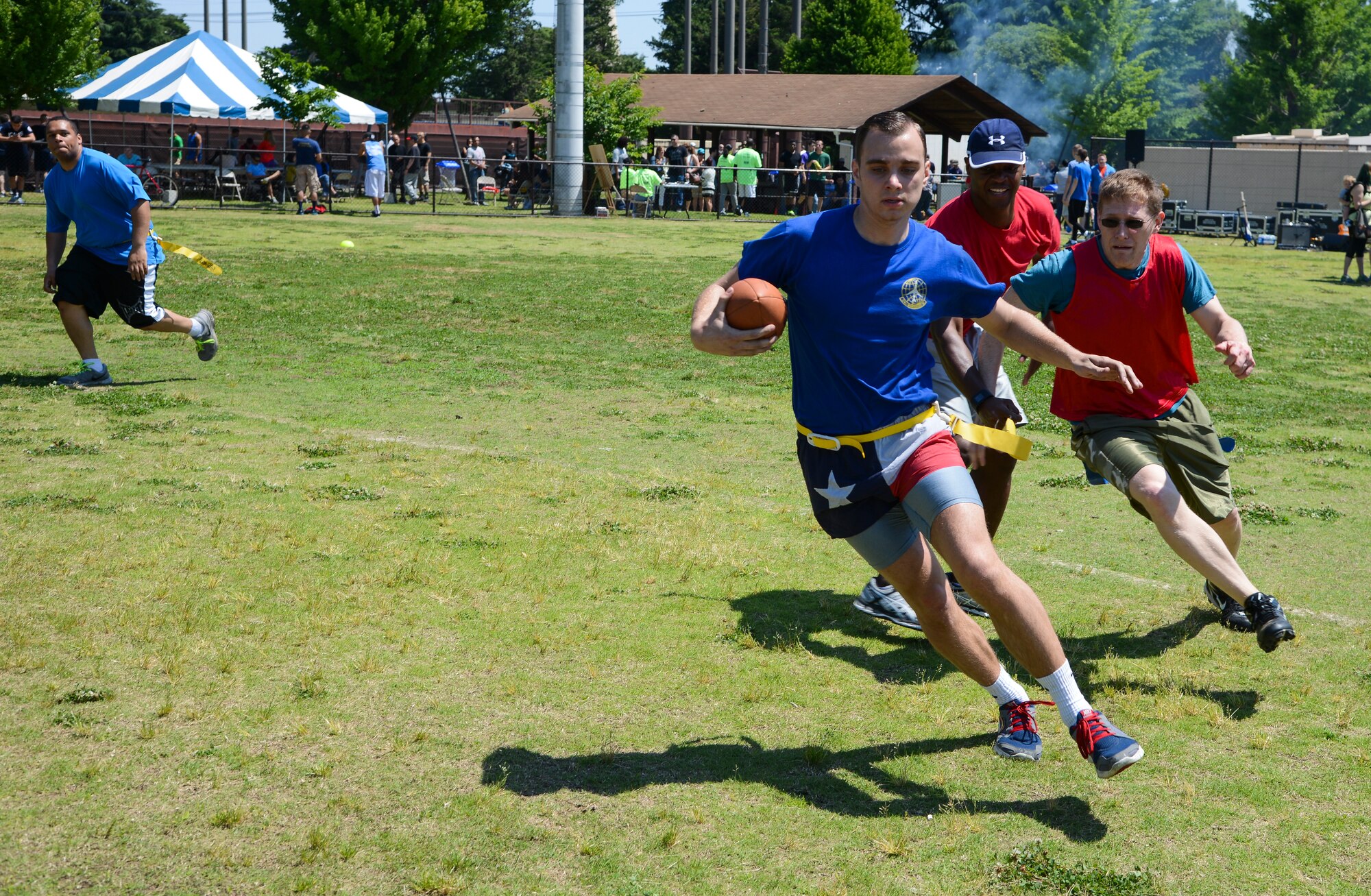 Colton Fisher, 374th Maintenance Squadron, scrambles away from defenders on the 374th Wing Staff Agency team May 21, 2015, during the Airman Appreciation Day at Yokota Air Base, Japan. Fisher’s flag was pulled after gaining 10-yards. (U.S. Air Force photo by Senior Airman David Owsianka/Released)