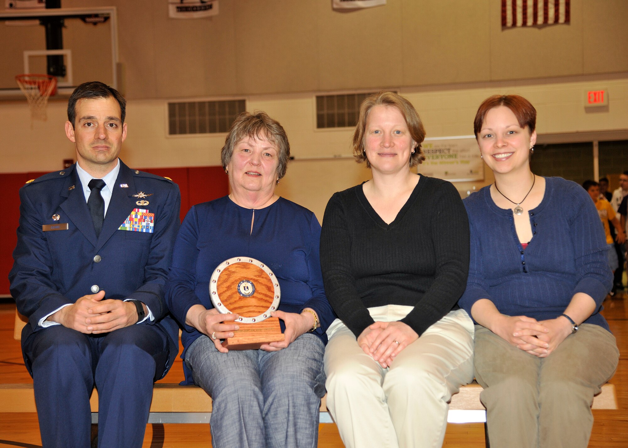 Maj. Matthew Suhre, 319th Communications Squadron commander, sits on a “buddy bench” with Jennifer Olson, Amy and Christina Waters, family members of Robert Olson on May 18, 2015, on Grand Forks Air Force Base, N.D. The bench, symbolizes a student in need of a friend to talk or to play with which will be placed at the playground in memory of Mr. Olson. Olson passed away on Oct. 15, 2014 at the age of 69 while battling prostate cancer.  (U.S. Air Force photo by Senior Airman Xavier Navarro/released)