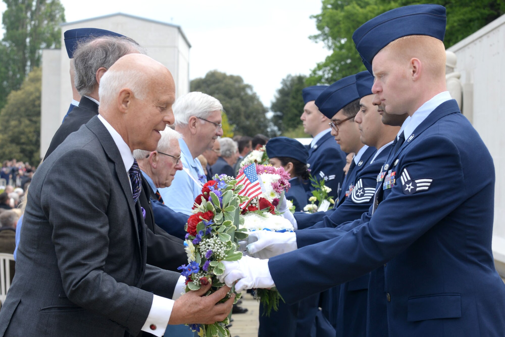 Designated wreath bearers receive their respective wreaths from RAF Mildenhall Airmen during the annual Memorial Day ceremony at the Cambridge American Cemetery and Memorial May 25, 2015, in Cambridge, England. The memorial service was held in memory of more than 400,000 American World War II service members who paid the ultimate sacrifice to preserve freedom. (U.S. Air Force photo by Senior Airman Kate Thornton/Released)