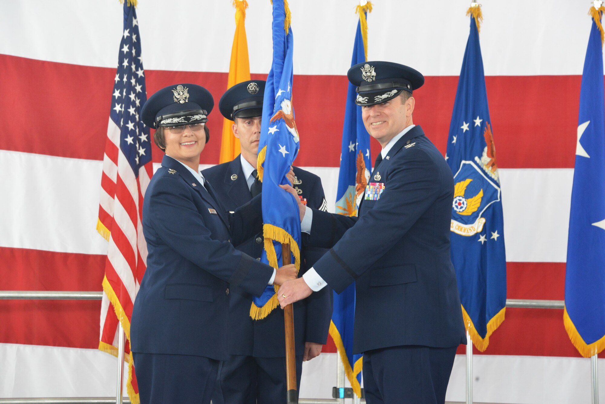 Col. Eric Froehlich, new 377th Air Base Wing and installation commander, takes the wing guidon from Maj. Gen. Sandra Finan (left), Air Force Nuclear Weapons Center commander, at a change of command ceremony May 21.  Froehlich was formerly the vice commander at Sheppard AFB, Texas.  (Photo by Dennis Carlson)