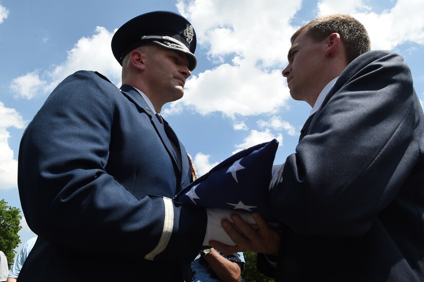 Air Force Maj. Ryan Vanveelen, U.S. Air Force Honor Guard director of operations, passes off a folded flag to Army Maj. Steven Curtis, North Carolina Defense Congressional fellow, following a ceremony in honor of Capt. Glenn Cook in front of the Vietnam Veteran’s Memorial, in Washington D.C., May 19, 2015. Cook’s plane was shot down near Nha Trang, Vietnam, Oct. 21, 1969. His remains were never found. (U.S. Air Force photo/Senior Airman Joshua R. M. Dewberry)