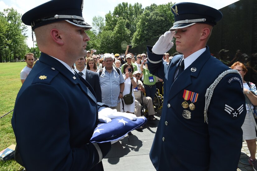 U.S. Air Force Honor Guardsmen salute a folded flag during a ceremony in honor of Capt. Glenn Cook in front of the Vietnam Veteran’s Memorial in Washington, D.C., May 19, 2015. Cook’s plane was shot down near Nha Trang, Vietnam, Oct. 21, 1969. His remains were never found. (U.S. Air Force photo/Senior Airman Joshua R. M. Dewberry)