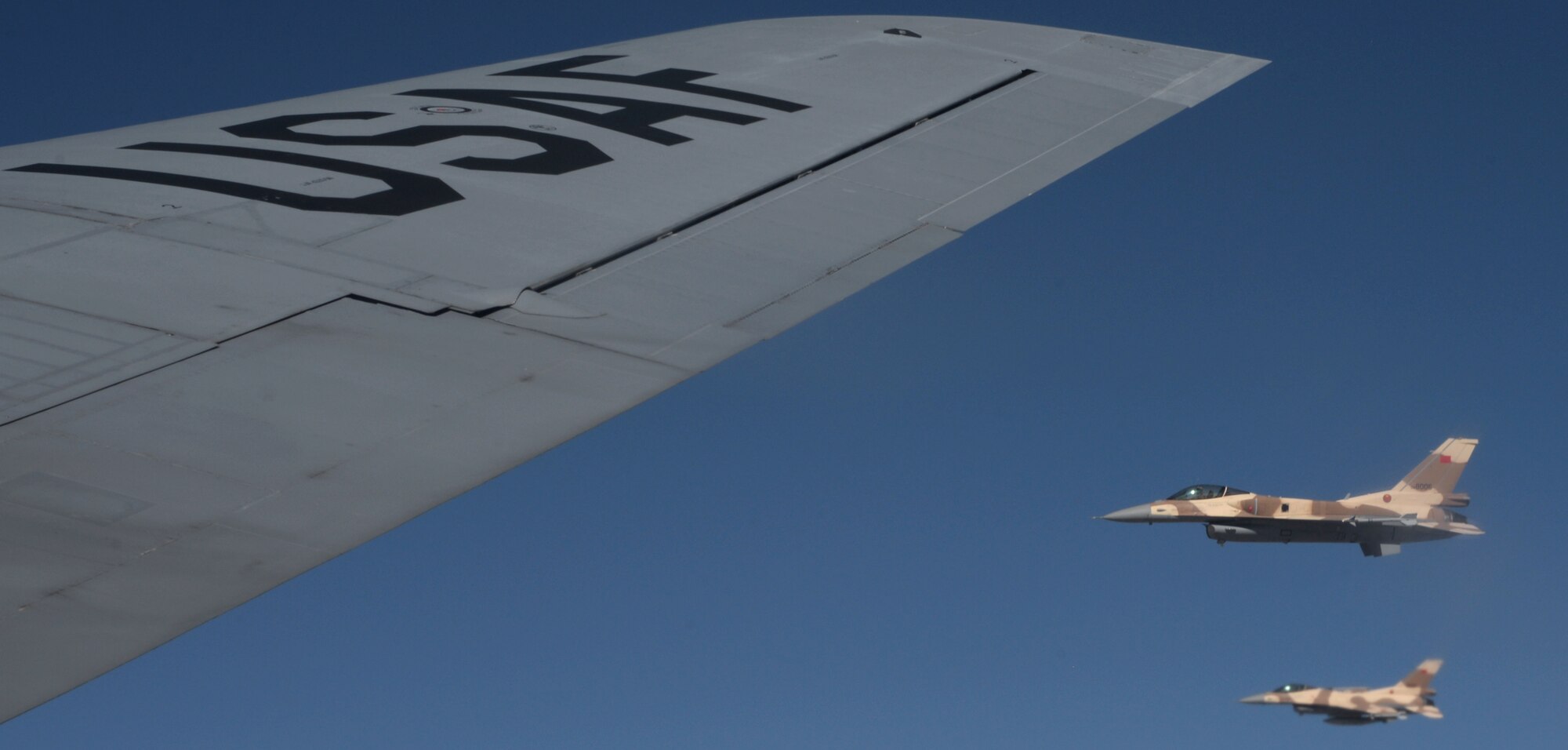 Two Royal Moroccan air force F-16 Fighting Falcons fly alongside the wing of a KC-135 Stratotanker assigned to RAF Mildenhall, England, while participating in Exercise African Lion May 18, 2015. The exercise features first-time integrated flying operations training and is the largest Department of Defense exercise in Africa (U.S. Air Force photo by Senior Airman Victoria H. Taylor/Released)