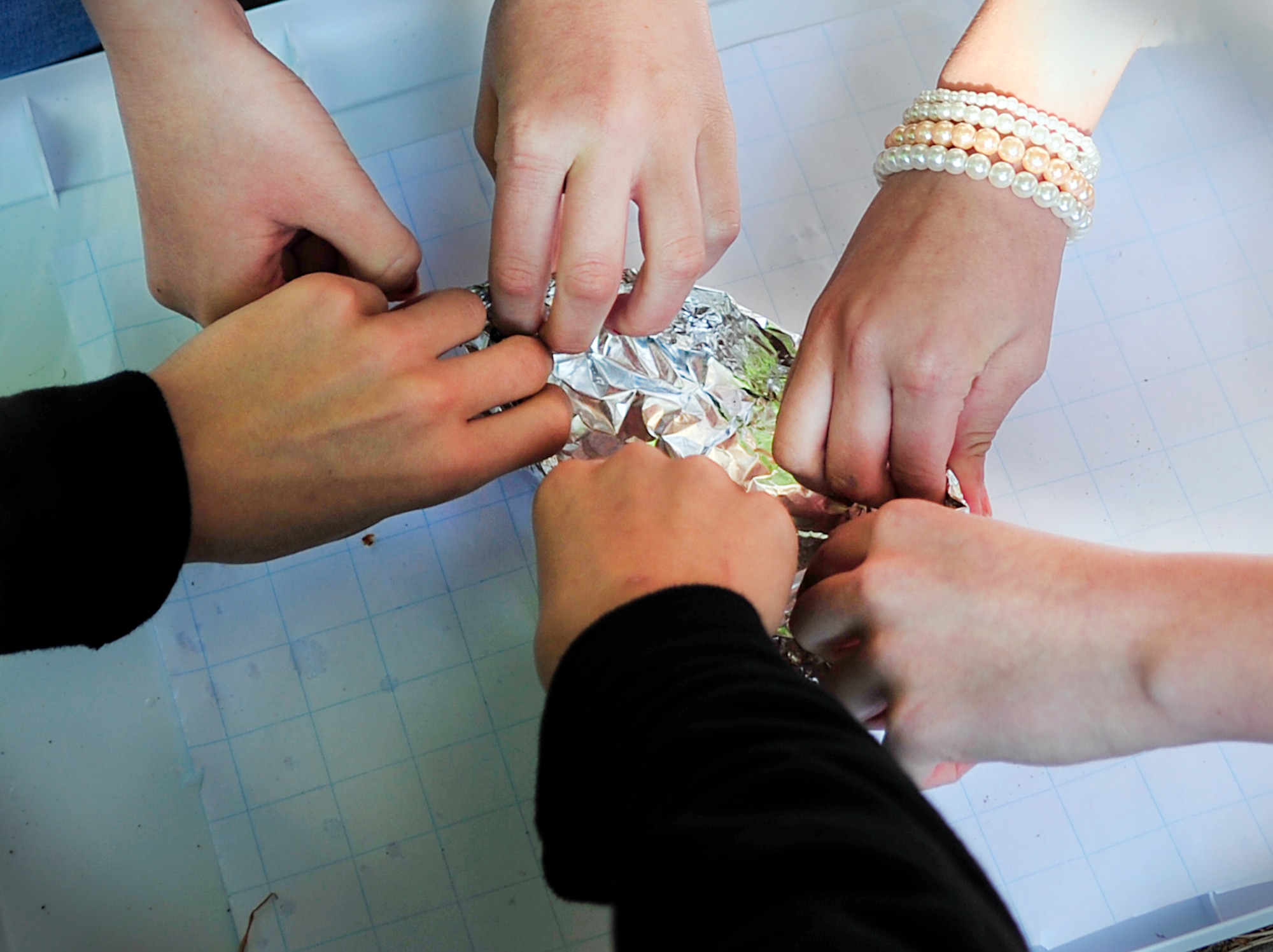 Middle school students work together to craft a boat out of aluminum foil as part of a STEMposium challenge May 13, 2015, at Ramstein Air Base, Germany. The students from middle schools throughout Germany came together to test their science, technology, engineering and math skills during the two-day event which offered them experience in solving real-world problems. (U.S. Air Force photo/Airman 1st Class Larissa Greatwood)