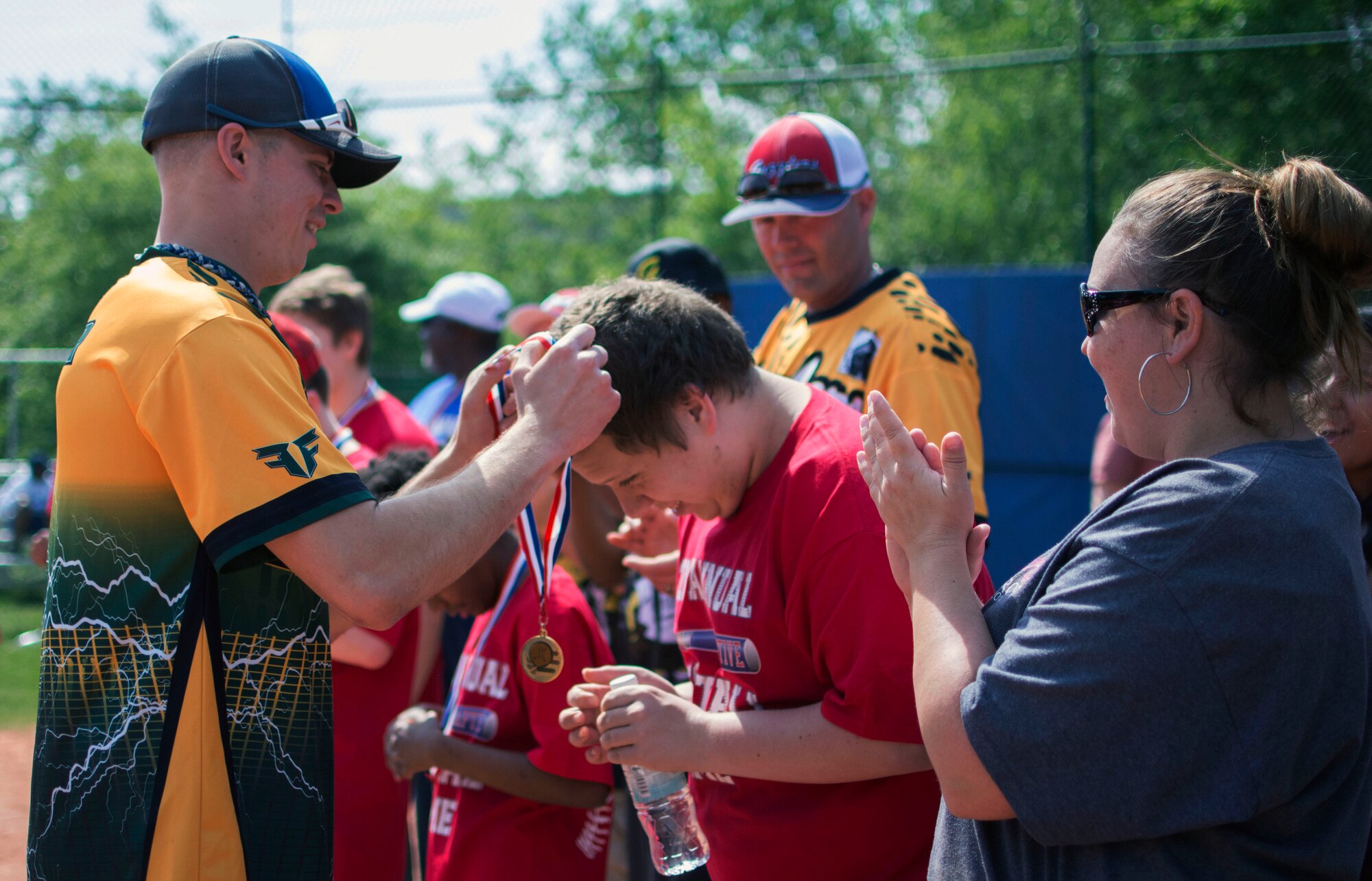 Senior Airman Bryan Painter, a volunteer from the 86th Maintenance Squadron, places a medal around the neck of Tyler Simon at the Ramstein High School softball field during the 2nd Annual Adaptive Softball Game on Ramstein Air Base, Germany, May 14, 2015. The event provides an opportunity for special needs children to participate in a healthy activity while receiving recognition for their efforts. (U.S. Air Force photo/Staff Sgt. Brandy Grace)