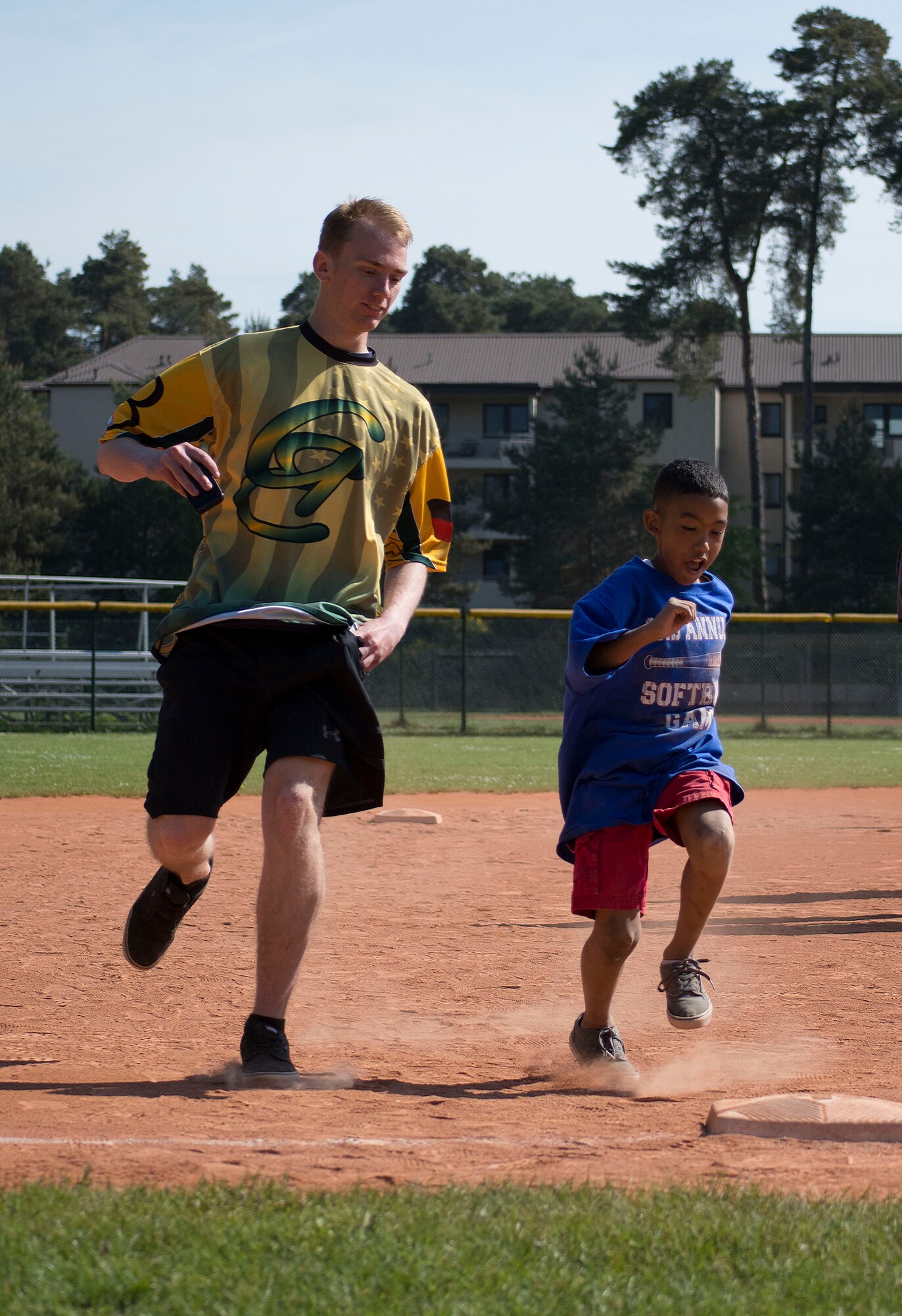Airman 1st Class Glennon Parks, a volunteer from the 86th Aircraft Maintenance Squadron, runs to third base alongside Elijah Muhammad at the Ramstein High School softball field during the 2nd Annual Adaptive Softball Game on Ramstein Air Base, Germany, May 14, 2015. The event provides an opportunity for special needs children to participate in a healthy activity while receiving recognition for their efforts. (U.S. Air Force photo/Staff Sgt. Brandy Grace)