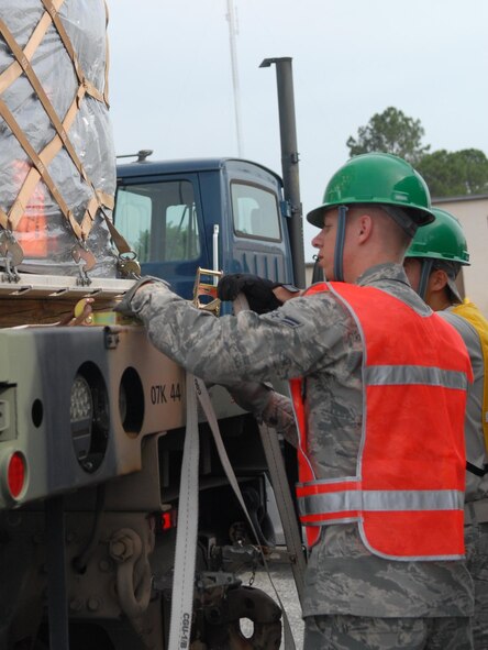 Two airmen strap a 96-inch-tall pallet to the bed of a truck for movement. The unit palletizes all its non-hand carry equipment, even if it will be convoyed instead of transported by air, May 14, 2015. (U.S. Air Force photo by Misuzu Allen)