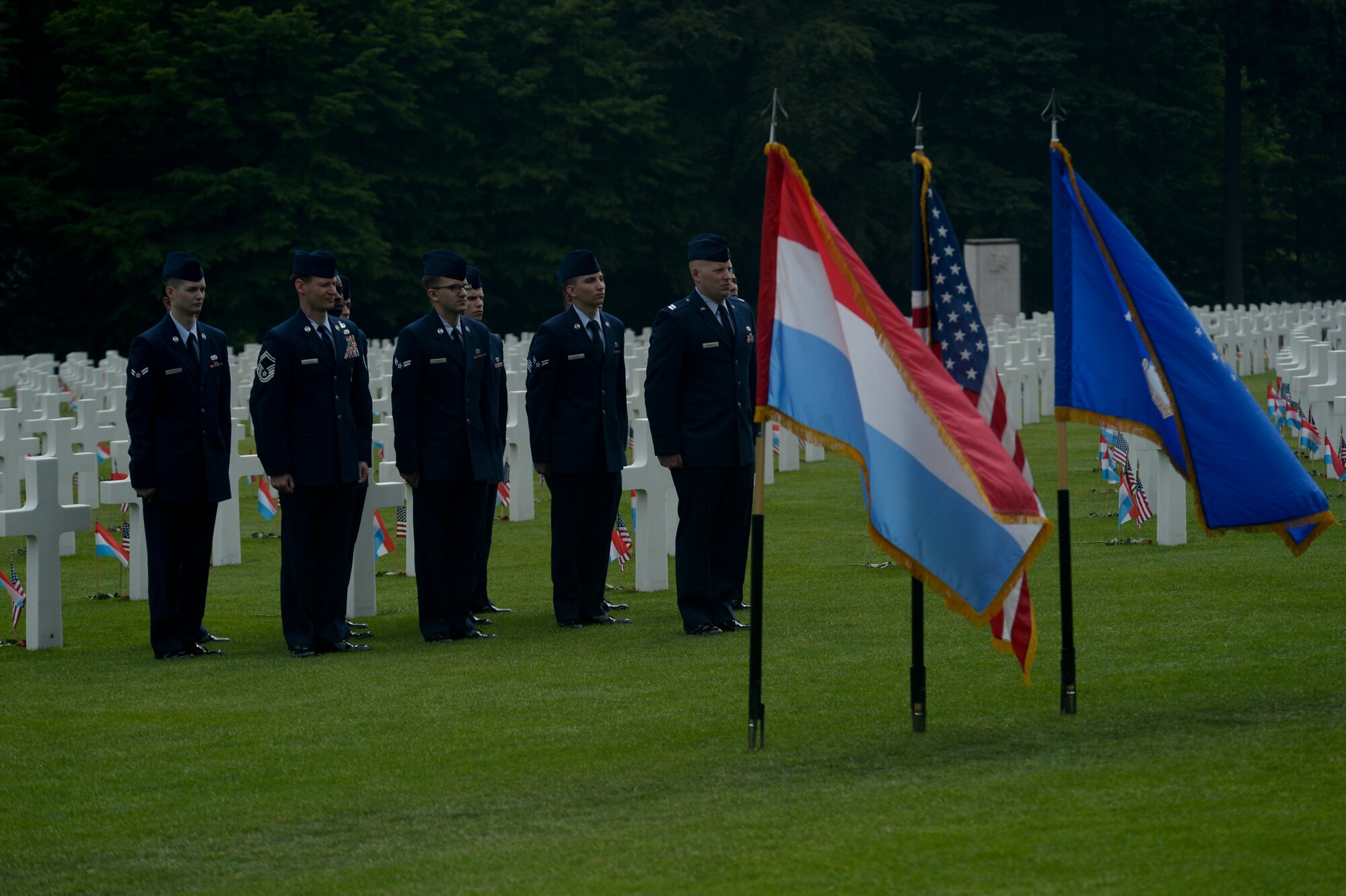 A flight of U.S. Air Force Airmen from the 52nd Fighter Wing at Spangdahlem Air Base, Germany, stand at attention before the Luxembourg, U.S. and U.S. Air Force flags during a Memorial Day ceremony at the Luxembourg American Cemetery and Memorial in Luxembourg, May 23, 2015. The base's Airmen also served as a ceremonial flight in service dress, caretakers of the cemetery's Luxembourg and U.S. flags, and escorts for guests to lay wreaths. (U.S. Air Force photo by Staff Sgt. Joe W. McFadden/Released)  