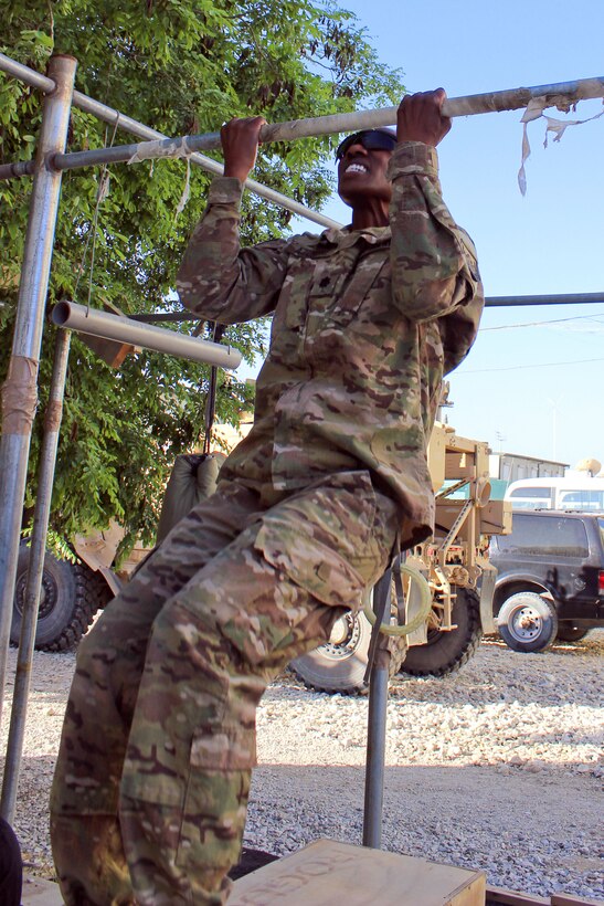 A soldier participates in pullups while wearing his body armor as part