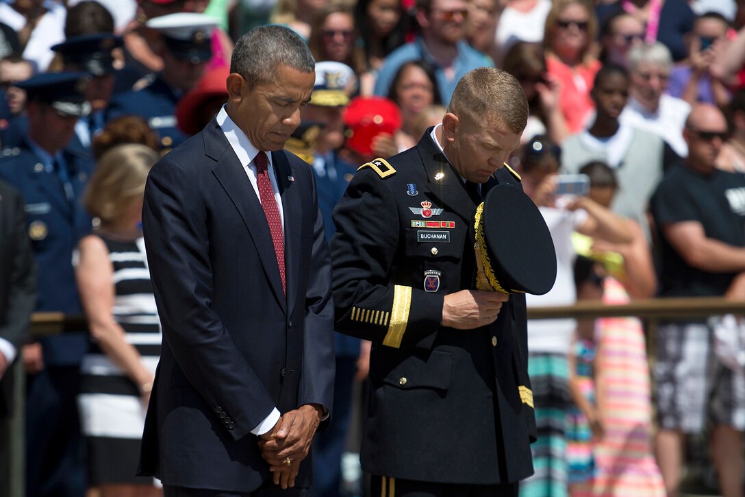 President Barack Obama, accompanied by Army Maj. Gen. Jeffrey S. Buchanan, commander of the U.S. Army Military District of Washington, bow their heads during the playing of “Taps” at the Tomb of the Unknown Soldier at Arlington National Cemetery in Arlington, Va., on Memorial Day, May 25, 2015.