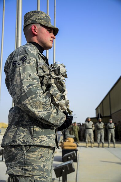 Senior Airman Gavin Barker, 379th Expeditionary Forces Squadron, holds the wreath at the position of attention at the start of the retreat ceremony at Memorial Plaza May 25, 2015, at Al Udeid Air Base, Qatar. The retreat ceremony was held on Memorial Day. It’s observed annually on the last Monday of May to commemorate the men and women who died while serving in the U.S. armed forces. (U.S. Air Force photo by Tech. Sgt. Rasheen Douglas)