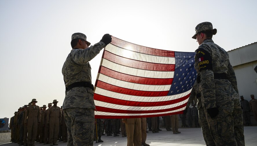 (From left) Senior Airman Enrique Caceres, 379th Expeditionary Civil Engineering Squadron, Airman 1st Class Samantha Healy, 379th Expeditionary Logistics Readiness Squadron, and Staff Sgt. Dave Colon, 379th Expeditionary Aeromedical Evacuation Squadron fold the flag in tribute to fallen Service members during a retreat ceremony Memorial Day May 25, 2015 on Al Udeid Air Base, Qatar. It’s observed annually on the last Monday of May to commemorate the men and women who died while serving in the U.S. armed forces.