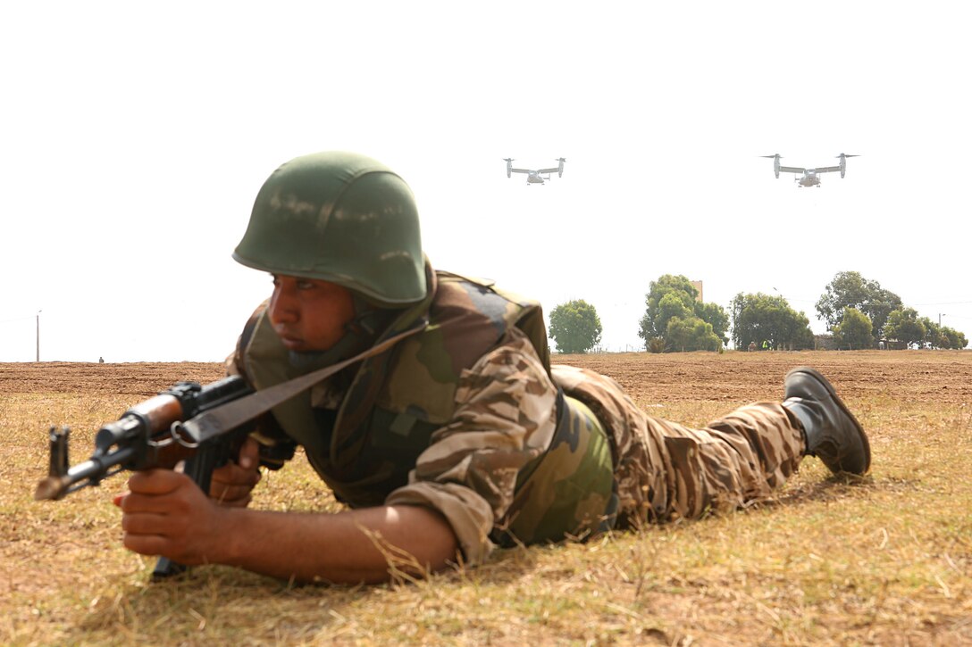 A Moroccan soldier provides security as a section of MV-22 Ospreys prepare to land and insert a contingent of Marines as reinforcement May 20 in the Tifnit, Morocco training area. A tilt-rotor insertion with security was one of several demonstrations for general officers from participating countries. The DV day was designed to allow observation of what had been accomplished during the week-long training at the camp as a part of Exercise African Lion 2015. Exercise African Lion 15 is an annually-scheduled, combined U.S.–Moroccan exercise designed to improve mutual understanding of each nation’s tactics, techniques and procedures while demonstrating the strong bond between the two nation’s militaries.  The one-week exercise includes various types of military training, including a command post exercise; stability operations, such as nonlethal weapons training and crisis/disaster response training.  Additionally, in February an intelligence capacity building seminar was conducted.