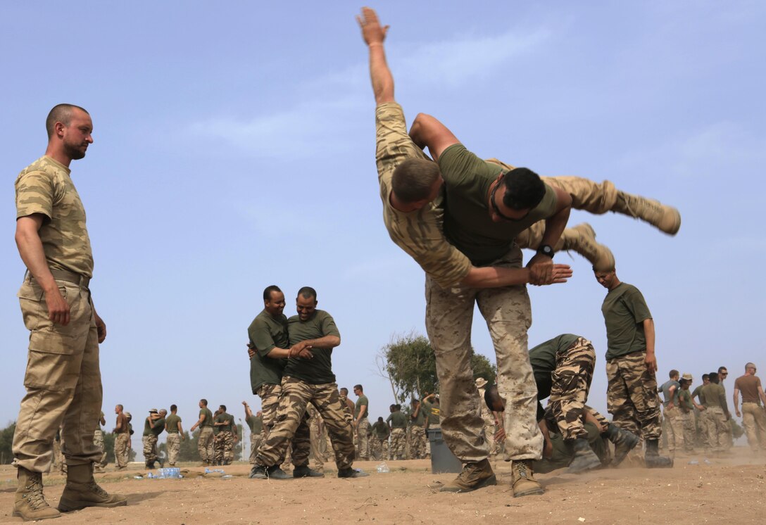 U.S. Marine Corps Cpl. Daniel Barker, 2nd Law Enforcement Battalion, hip-throws a Belgian soldier to practice nonlethal take-down techniques during Exercise African Lion 15, May 15, in Tifnit, Morocco. The Royal Moroccan, U.S., U.K., Netherlands, and Belgian Armed Forces integrated while conducting peacekeeping support training to improve military capabilities and operational familiarity as one international coalition.