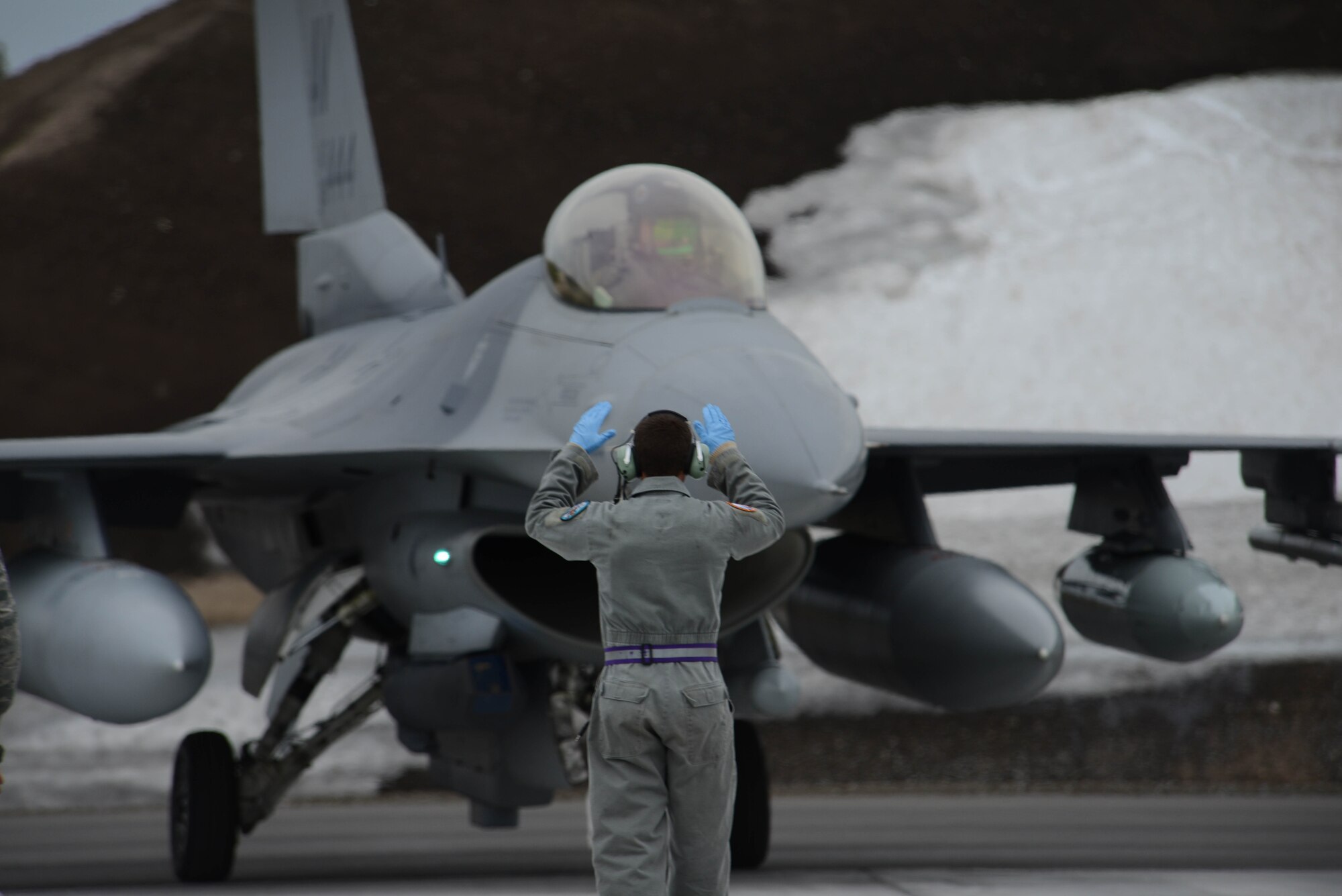 An Airman with the 510th Fighter Squadron from Aviano Air Base, Italy, guides an F-16 Fighting Falcon at Kallax Air Base, Sweden, May 22, 2015. The 510th FS took part in Arctic Challenge Exercise 2015. Nine nations also participated during the exercise to help ensure interoperability, and strengthen relationships and engagements with NATO allies and Partners for Peace. (U.S. Air Force photo/Staff Sgt. Evelyn Chavez)