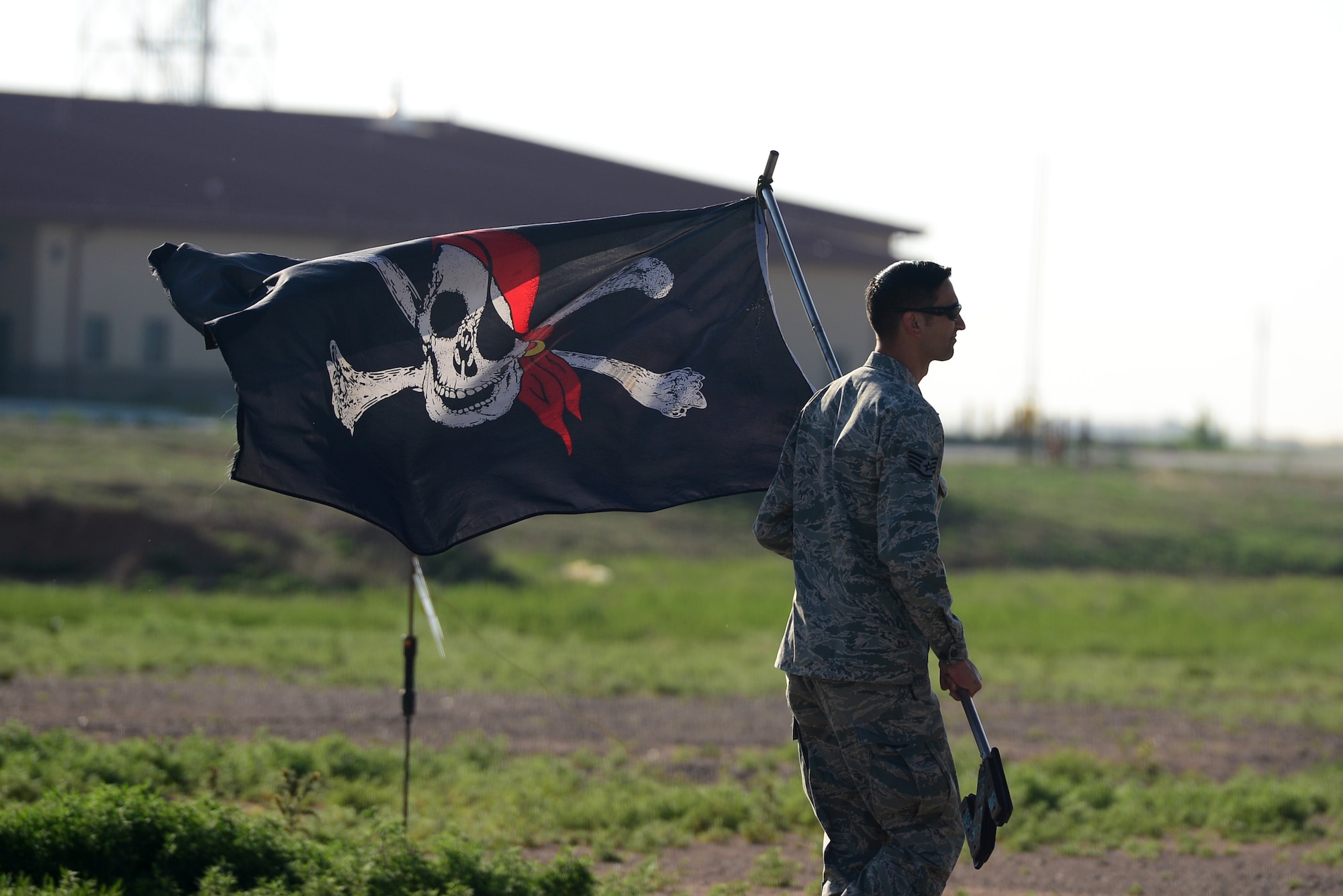 U.S. Air Force Staff Sgt. Samuel Pearson, 27th Special Operations Aircraft Maintenance Squadron maintenance training instructor, carries the “Jolly Roger” flag to the AC-130H Spectre gunship, nicknamed “Excalibur”, May 27, 2015 at Cannon Air Force Base, N.M. The “Jolly Roger” is a pirate flag flown to boost morale and was displayed during the final Spectre gunship deployment. (U.S. Air Force photo/Senior Airman Eboni Reece)