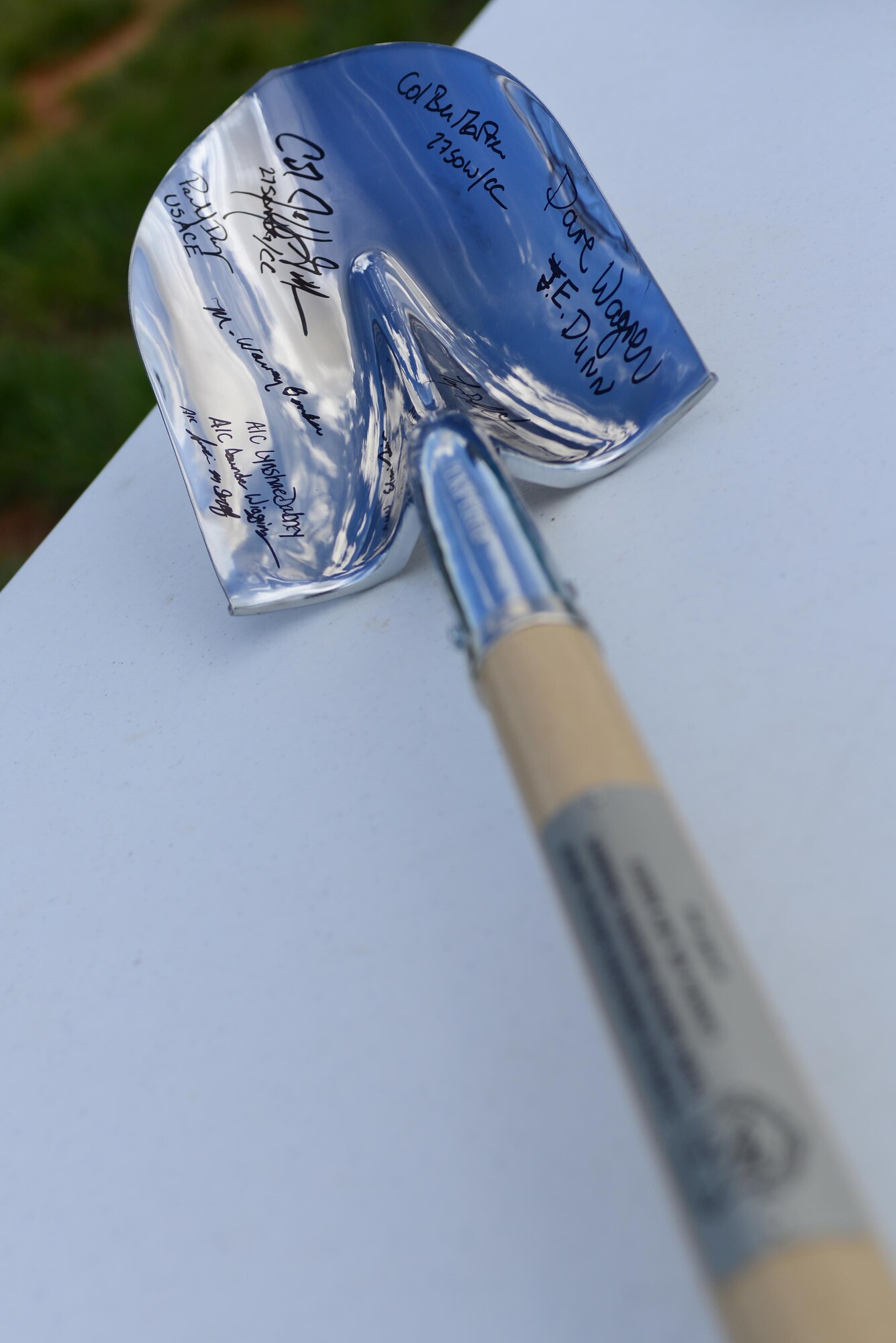 Participants from the groundbreaking ceremony autograph a shovel to be kept as a memento of the medical clinic groundbreaking ceremony, May 26, 2015 at Cannon Air Force Base, N.M. The ceremony was held to signify the commencement of the Cannon medical clinic replacement project. (U.S. Air Force photo/ Senior Airman Eboni Reece)