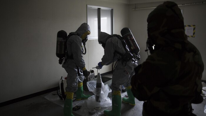 Marines contain a leaking ordnance round during leak, seal, package and decontamination training April 21 at the gas chamber on Camp Hansen, Okinawa. Explosive ordnance disposal technicians and chemical, biological, radiological, nuclear defense specialists placed a leaking ordnance package in the gas chamber, using chlorobenzylidene malonitrile, also known as tear gas, to simulate the emission of harmful gases. 