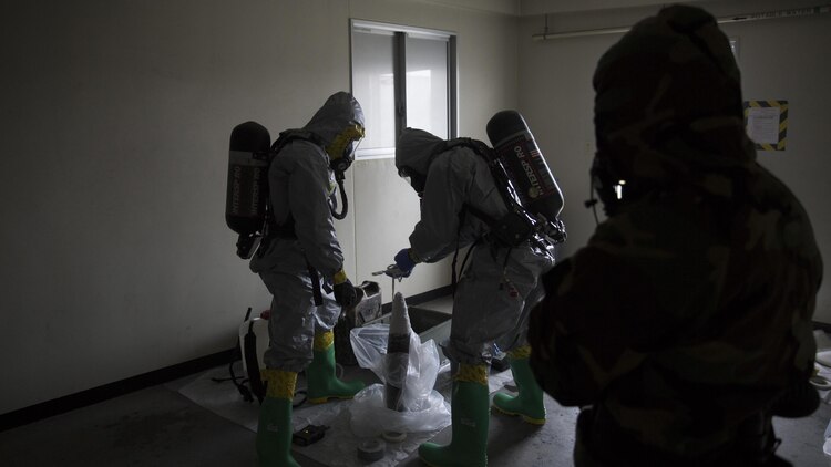 Marines contain a leaking ordnance round during leak, seal, package and decontamination training April 21 at the gas chamber on Camp Hansen, Okinawa. Explosive ordnance disposal technicians and chemical, biological, radiological, nuclear defense specialists placed a leaking ordnance package in the gas chamber, using chlorobenzylidene malonitrile, also known as tear gas, to simulate the emission of harmful gases. 