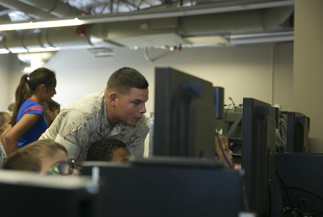 Lance Cpl. Richard Hedges, tank gunner, 1st Tank Battalion, helps students from Palm Vista Elementary School operate the Advanced Gunnery Training System during a tour of the Tank Ramp, May 18, 2015. Thirty-five Marines volunteered to work with the children during the tour. (Official Marine Corps photo by Lance Cpl. Thomas Mudd/ Released)