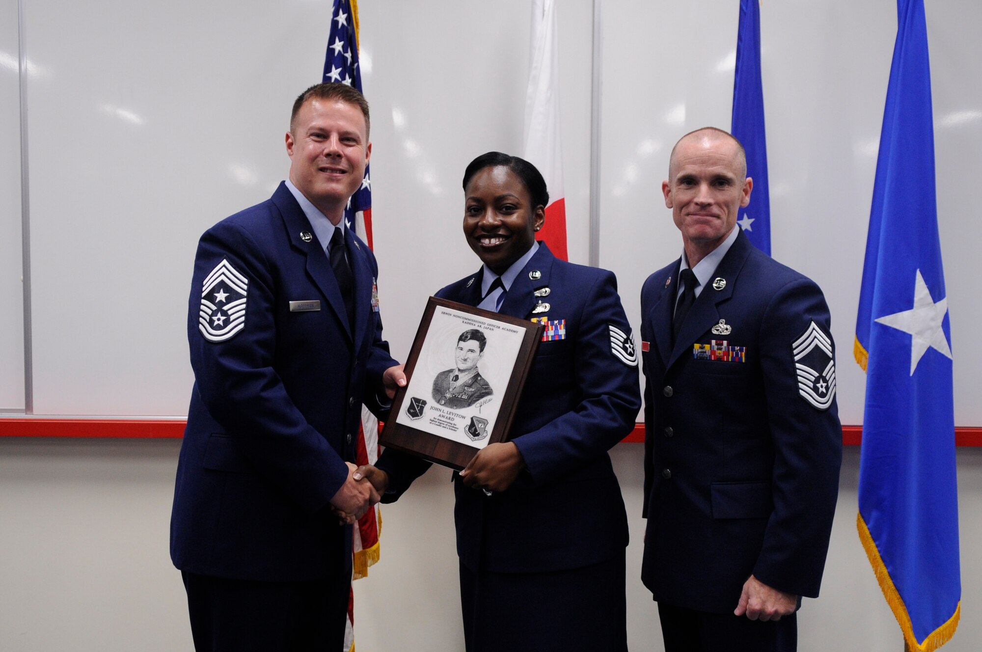 U.S. Air Force Chief Master Sgt. Charles Hoffman, 18th Wing command chief, presents Tech. Sgt. Jessica Player, 374th Force Support Squadron, Misawa Air Base, Japan, the John L. Levitow award during the NCO Academy Class 15-4 at the Professional Military Education center  on Kadena Air Base, Japan, May 22, 2015. This distinguished graduate award, named in memory of Medal of Honor recipient Airman 1st Class John L. Levitow, is presented to the most outstanding member of professional military education and denotes superior achievement as both a leader and a scholar. (U.S. Air Force photo by Staff Sgt. Marcus Morris/Released)