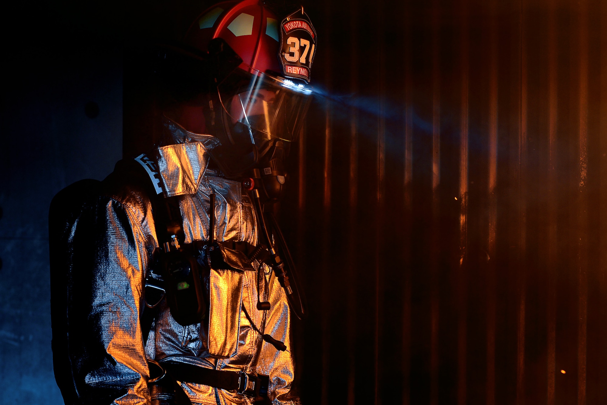 Staff Sgt. Joshua Reynolds, 374th Civil Engineer Squadron firefighter, peers at a fire during a joint fire training scenario May 26, 2015, at Yokota Air Base, Japan. Reynolds said that this training was a great and amazing opportunity to work and learn with his Japan Air-Self Defense force peers. (U.S. Air Force photo by Airman 1st Class Delano Scott/Released)