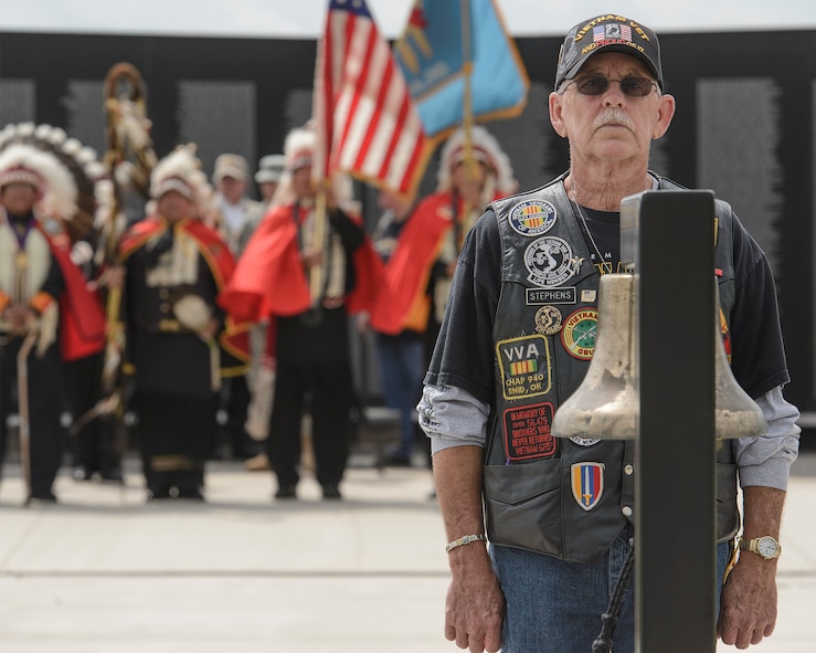 Larry Stephens, the secretary and treasurer of Vietnam Veterans of America Post 990, stands at the Vietnam Memorial Wall at Enid Woodring Municipal Airport in Enid, Oklahoma, May 25. Stephens tolled the bell as the newly-inscribed names of seven Vietnam veterans were unveiled and five other names had their statuses officially changed from Missing in Action to Killed in Action after their remains were recently returned home. (U.S. Air Force photo / David Poe)