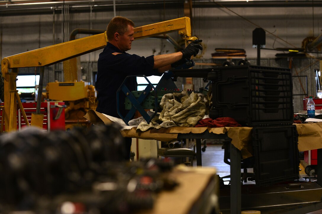 U.S. Army Sgt. Jeff Schweiger, 2nd Staff and Faculty Company Watercraft Engineer Certification Course student, attaches an engine head to an engine lift at Fort Eustis, Va., May 21, 2015. When attaching the head, consisting of valves and fuel injectors that provide air and fuel to the engine, Schweiger conducted an engine rebuild as part of the certification course. (U.S. Air Force photo by Staff Sgt. Natasha Stannard/Released)
