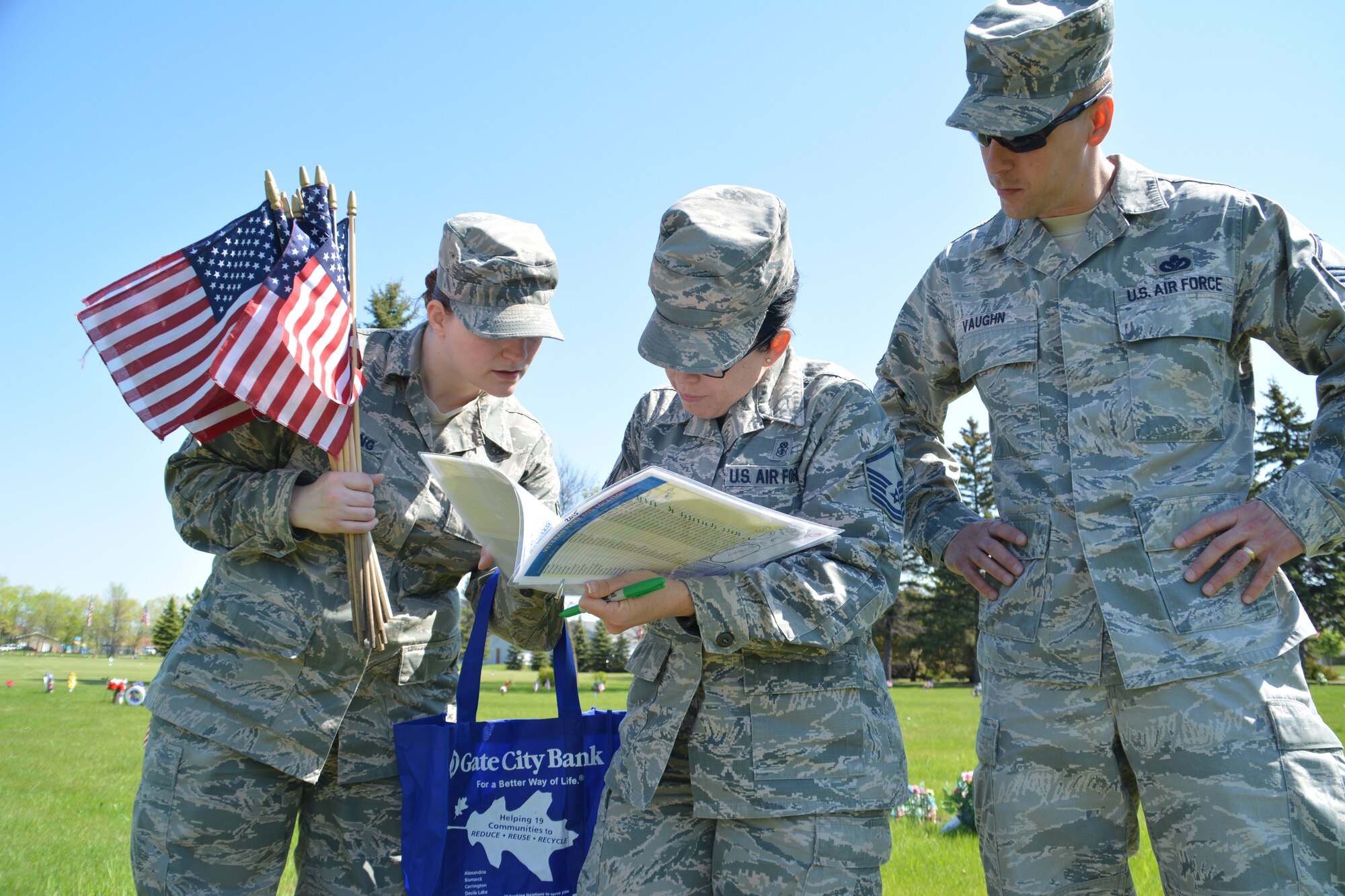 Staff Sgt. Vera Pickering, Master Sgt. Kristi Charles and Master Sgt. Michael Vaugh examine a list identifying veterans' gravesites May 22, 2015, at Memorial Park South Cemetery in Grand Forks, N.D.  The trio was part a group of more than 200 Airmen and family members from Grand Forks Air Force Base, N.D., who volunteered to place small U.S. flags on the tombs of deceased service members at two different cemeteries in in the city of Grand Forks. (U.S. Air Force photo/Staff Sgt. Luis Loza Gutierrez)
