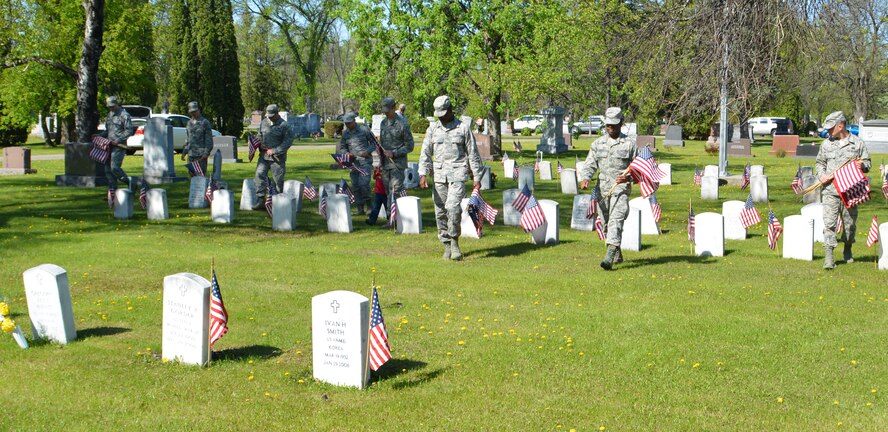 Volunteers from Grand Forks Air Force Base, N.D., walk through the grounds of Memorial Park Cemetery in the city of Grand Forks, N.D., looking for more U.S. veteran gravesites to places small U.S. flags by, May 22, 2015. More than 200 Airmen and family volunteers observed Memorial Day by placing small flags over 32 acres of cemetery plots that serve as the final resting place for more than 1,000 U.S. service members. The flags were provided by American Legion Post #6 of Grand Forks. (U.S. Air Force photo/Staff Sgt. Luis Loza Gutierrez)