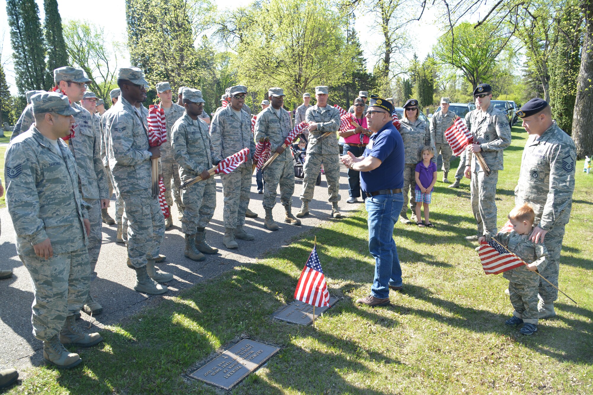 Retired Senior Master Sgt. Bob Greene, American Legion Post 6 commander, gives some quick instructions to a group of volunteers on where to place U.S. flags at Memorial Cemetery in Grand Forks, N.D., on May 22, 2015. More than 200 Airmen and family members from Grand Forks Air Force Base, N.D., volunteered to place small flags on the tombs of deceased service members in honor of Memorial Day. (U.S. Air Force photo/Staff Sgt. Luis Loza Gutierrez)