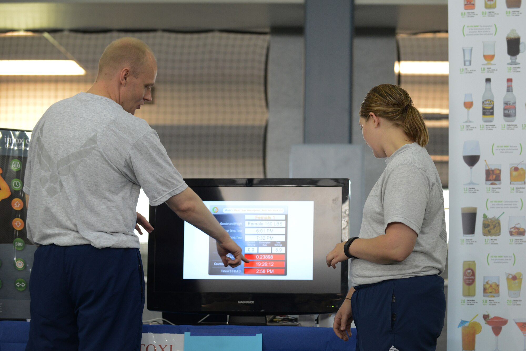 U.S. Air Force Tech. Sgt. Jeremy Goldston, the 354th Medical Operations Squadron mental health flight chief, shows how long it would take for alcohol to run through the system of Staff Sgt.  Candice Keene, the 354th Communications Squadron spectrum manager, based off the number of drinks she chose at the Alcohol Awareness and Safety Expo May 21, 2015, at the Baker Field House on Eielson Air Force Base, Alaska. The purpose of the Intoxi-clock was to show how many calories are consumed in a night of drinking and how long it takes for alcohol to leave the system. (U.S. Air Force photo by Senior Airman Ashley Nicole Taylor/Released)