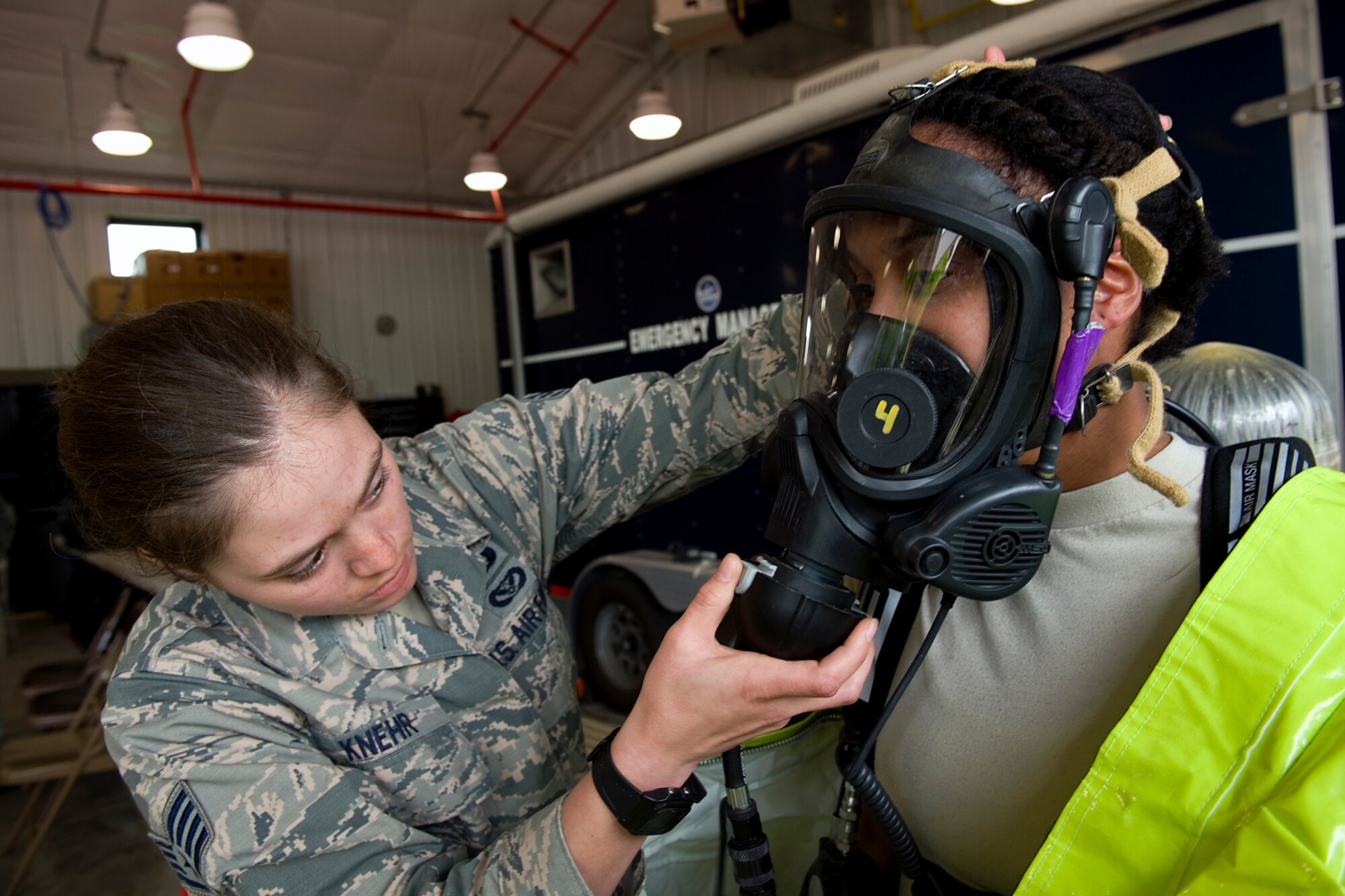 Staff Sgt. Alisha Knehr, Air Mobility Command emergency management specialist from McConnell Air Force Base, assists Airman 1st Class Simone Wilson, 319th Civil Engineer Squadron EM specialist from Grand Forks Air Force Base, N.D., with her oxygen mask during a chemical, biological, radiological, nuclear and enhanced conventional weapons training exercise at Grissom Air Reserve Base, Ind., May 19, 2015. The exercise was part of a 10-day course that allowed EM specialists from five major commands to unite and hone EM principals while incorporating combat skills and obtaining mandated recertifications. (U.S. Air Force photo/Tech. Sgt. Benjamin Mota)