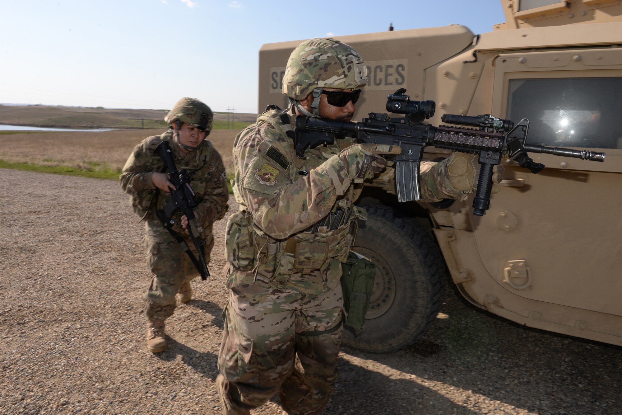 Senior Airman Rapheal Dexter, of the 91st Missile Security Forces Squadron, right, leads Staff Sgt. Shareen Mendiola, of the 219th Security Forces Squadron, as they advance on simulated intruders while utilizing a High Mobility Multipurpose Wheeled Vehicle (HMMWV), commonly known as a Humvee, for cover during a training exercise at a Minot Air Force Base, North Dakota, launch facility during a training exercise May 20, 2015. The exercise included an intermingled combination of North Dakota Air National Guard members doing their annual training and 91st Missile Security Forces Squadron members performing their day-to-day duties. The Air National Guard members are routinely integrated among the U.S. Air Force active duty personnel as they perform the real-World mission of missile field security in a seamless and indistinguishable manner. (U.S. Air National Guard photo by Senior Master Sgt. David H. Lipp/Released)