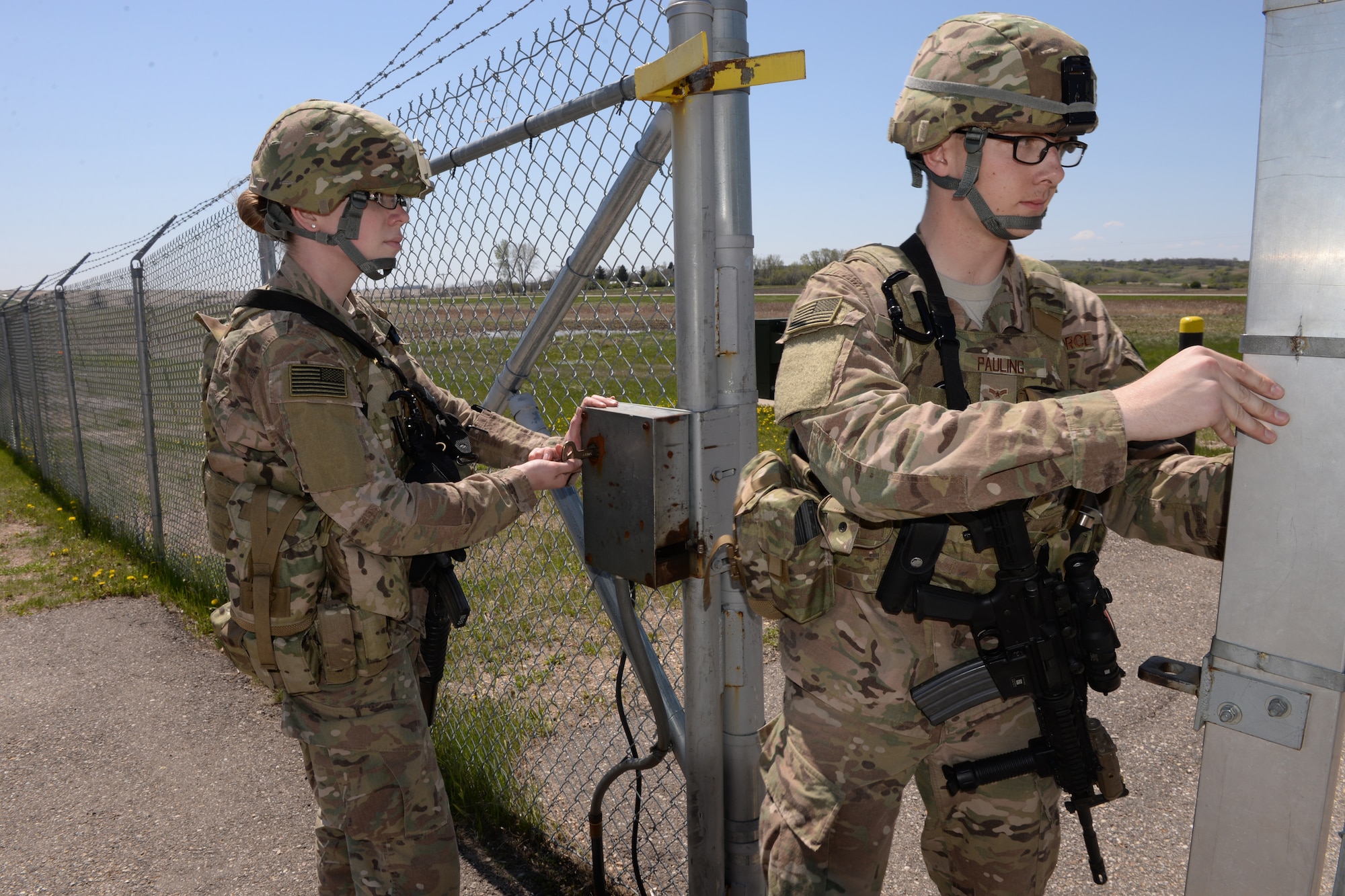 Members of the 219th Security Forces Squadron from left to right Airman 1st Class Angela Lage and Airman 1st Class Alex Pauling pass through a gate at a Minot Air Force Base, North Dakota, missile alert facility May 20, 2015, as they sweep the area for anything suspicious. The North Dakota Air National Guard members are doing their annual training period as they perform the real-World mission of missile field security, and train for their war-time tasking mission. The Air National Guard members are routinely integrated among the U.S. Air Force active duty personnel performing missile field security in a seamless and indistinguishable manner. (U.S. Air National Guard photo by Senior Master Sgt. David H. Lipp/Released)